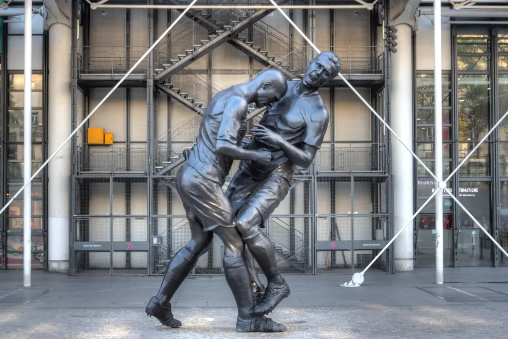 Estátua de bronze representando Zinedine Zidane em campo.