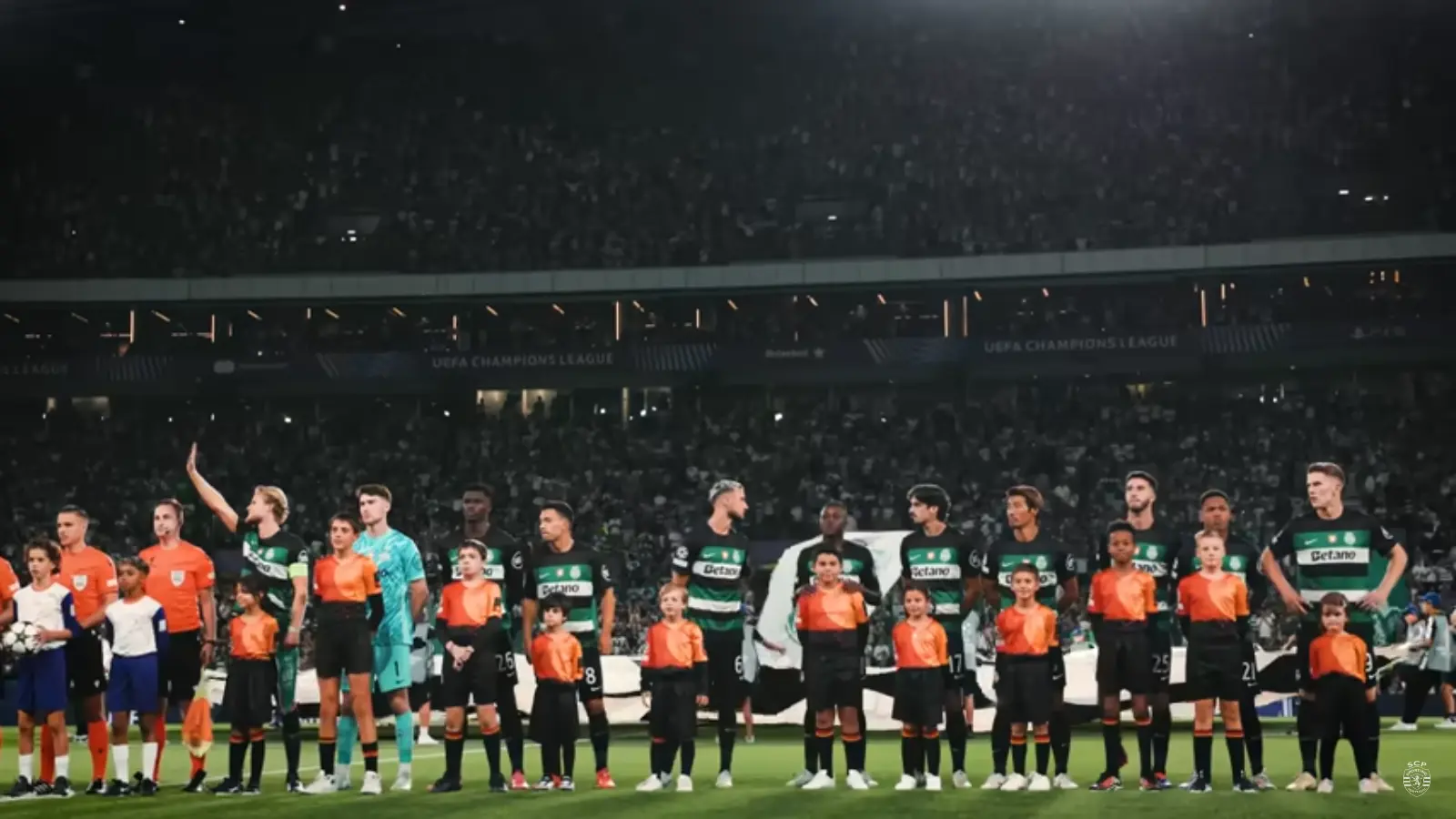 Jogadores do Sporting CP alinhados no campo com as crianças durante a UEFA Champions League.